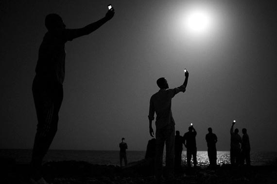 Фотограф Джон Стенмейер из США снял по заказу National Geographic африканских мигрантов на побережье Джибути, пытающихся поймать слабый сотовый сигнал из Сомали. Снято в феврале 2013 года<br />
